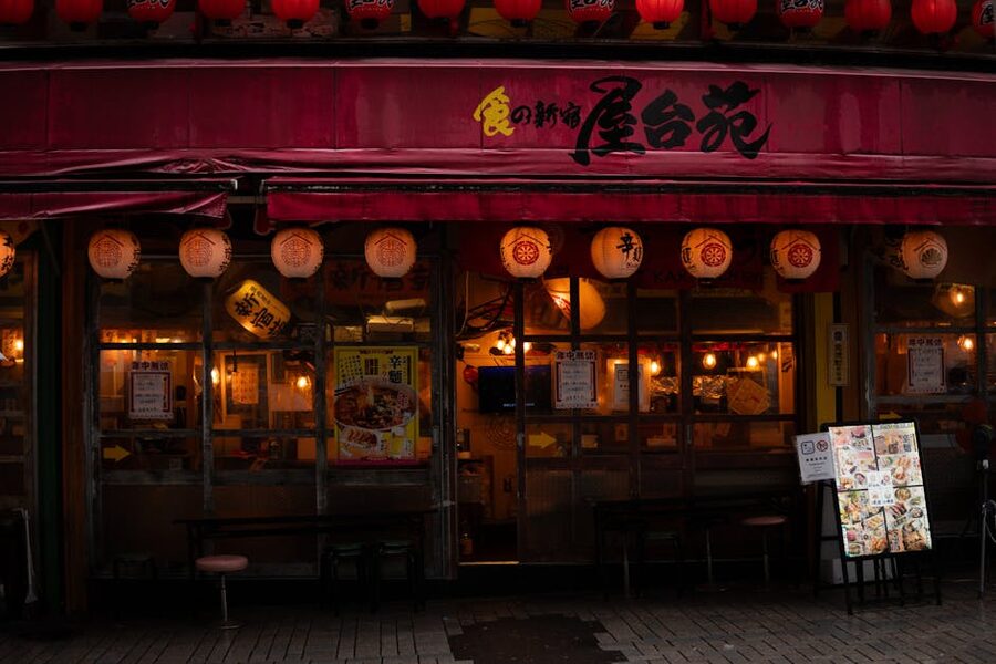 A traditional Japanese restaurant exterior at night with red lanterns and warm lighting, evocative of Osaka's drinking lanes