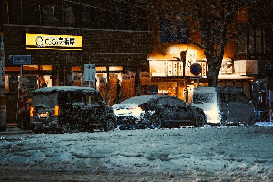 A small Tokyo restaurant on a snowy night with cars and warm lights, classic winter atsukan setting