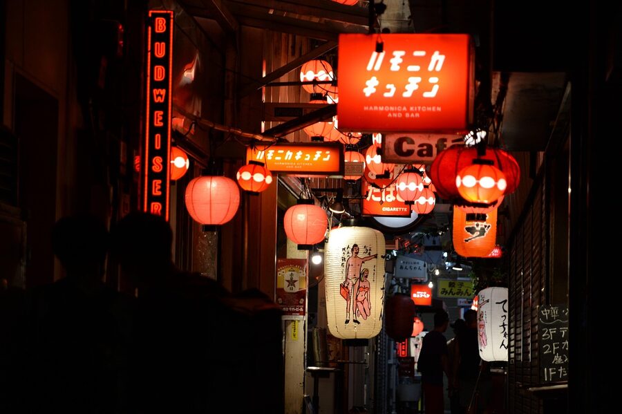 A small izakaya counter with hanging menus and a chef behind it