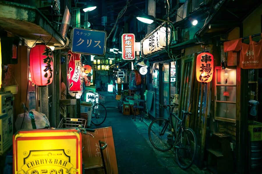 Red paper lanterns hanging over a narrow Tokyo backstreet at night