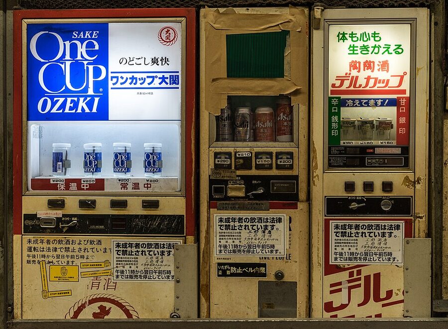 Old-style Japanese vending machines stocked with cup sake and beer