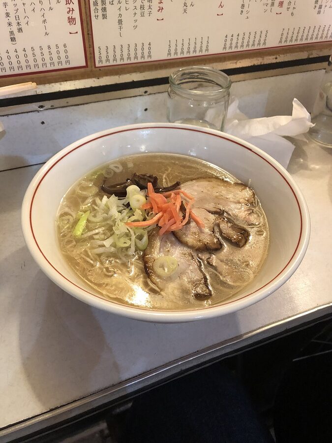 Close-up of milky pork-bone broth and thin Hakata ramen noodles