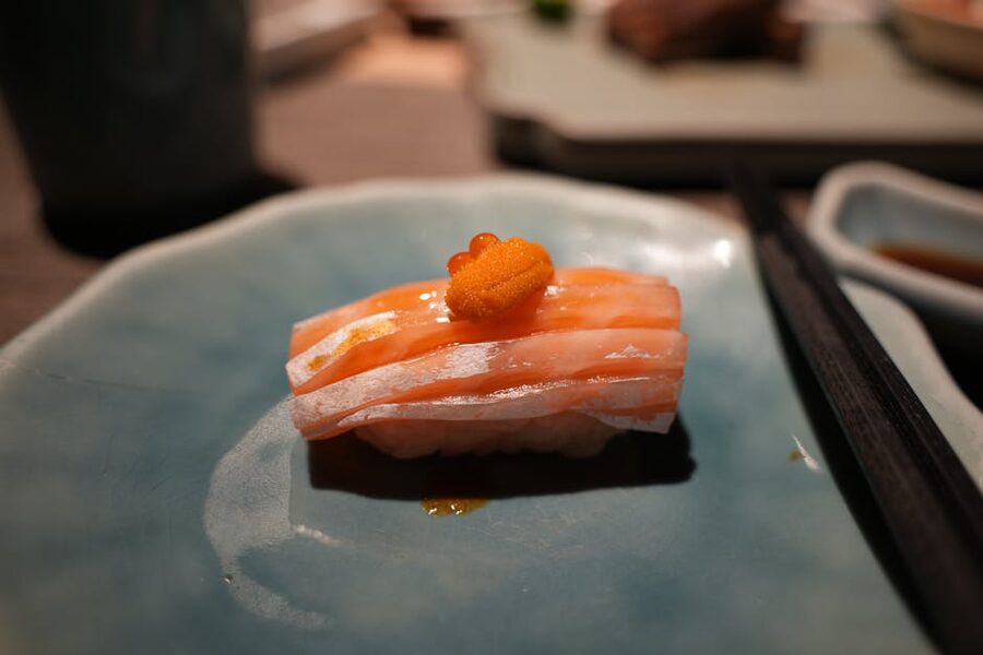 Salmon nigiri sushi topped with fish roe on a ceramic plate