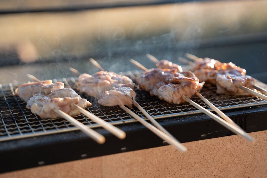 Skewers cooking on a small outdoor charcoal grill