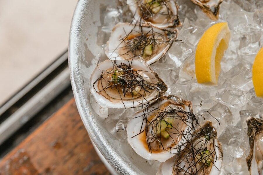 Plate of fresh oysters on crushed ice with lemon wedges
