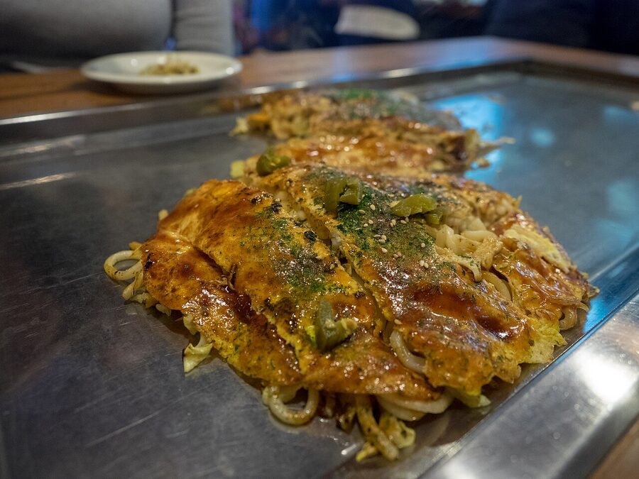 Overhead shot of finished Hiroshima okonomiyaki with brown sauce mayonnaise and bonito flakes