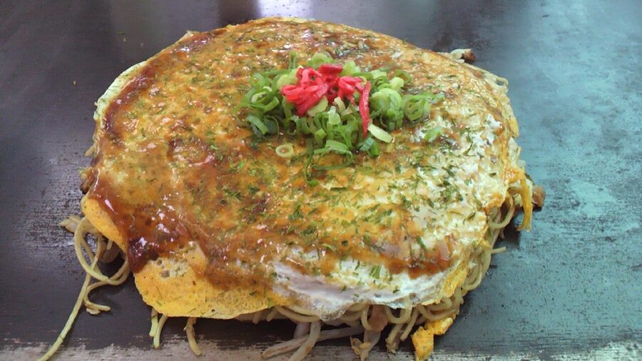 Cross section view of Hiroshima okonomiyaki showing layered cabbage pork noodles batter and egg