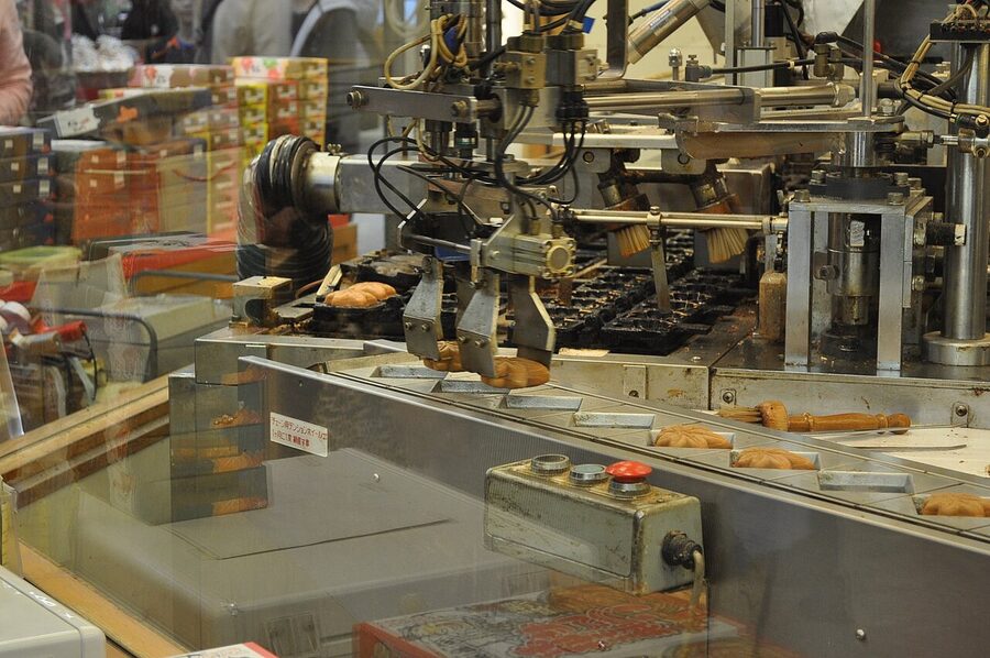 Mechanical momiji manju maker dispensing maple-shaped cakes onto a tray
