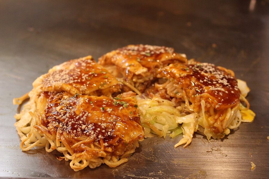 Finished Hiroshima okonomiyaki on a hot plate sliced ready to eat