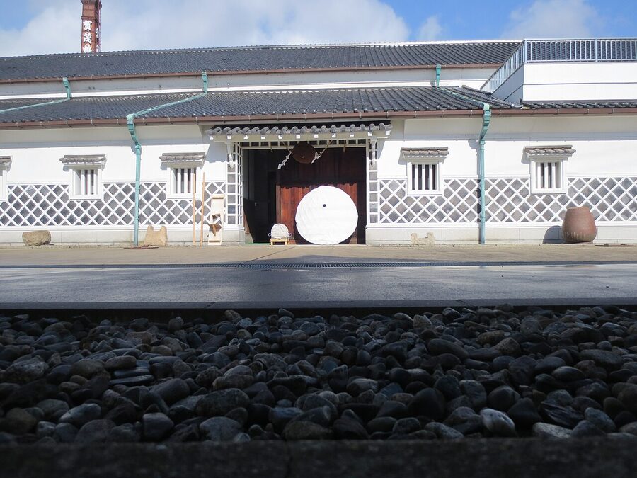 Interior of a Saijo sake brewery with traditional brewing equipment and earthenware vessels
