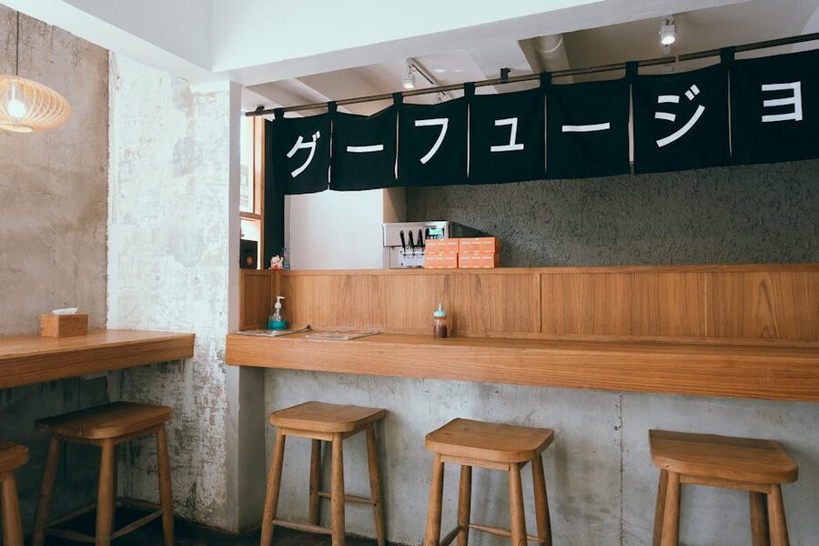 Modern izakaya interior with wooden stools, table-side tablets visible, and minimalist signage