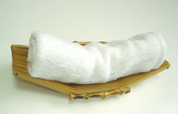 Rolled white oshibori hot towel on a wooden tray