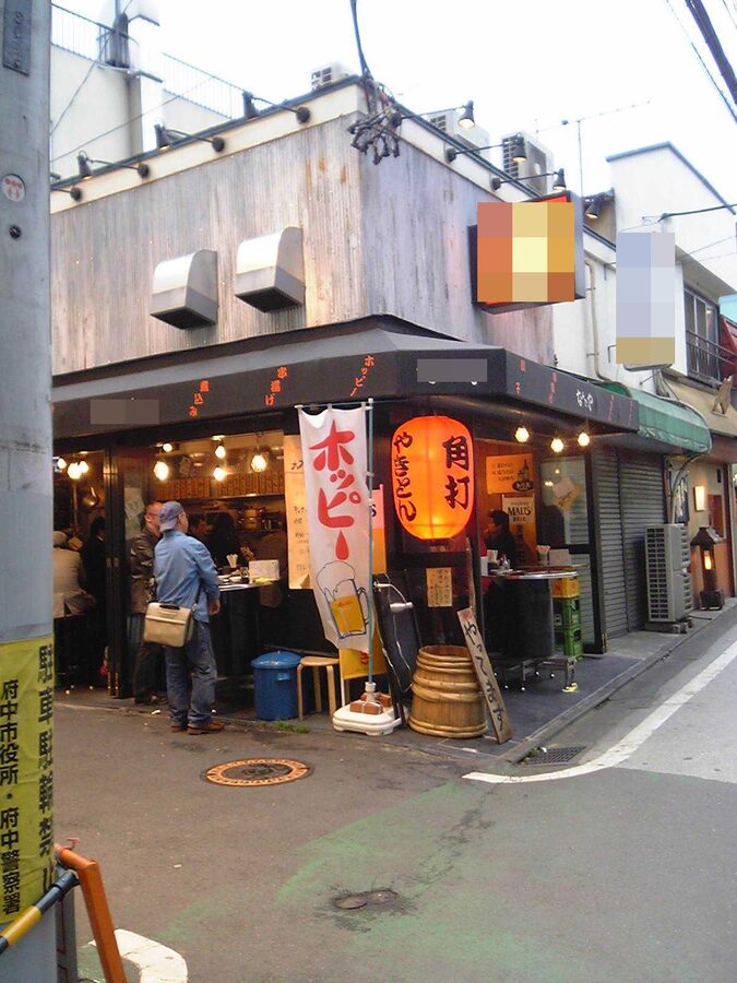 A small tachinomi standing bar with patrons drinking at a high counter in Tokyo