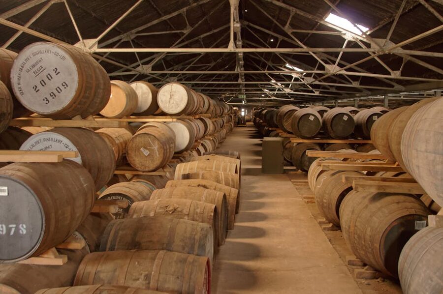 Whisky barrels aging in a long warehouse