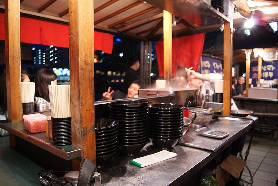 Yatai food stall along the Naka River in Fukuoka with hanging menu and seated customers