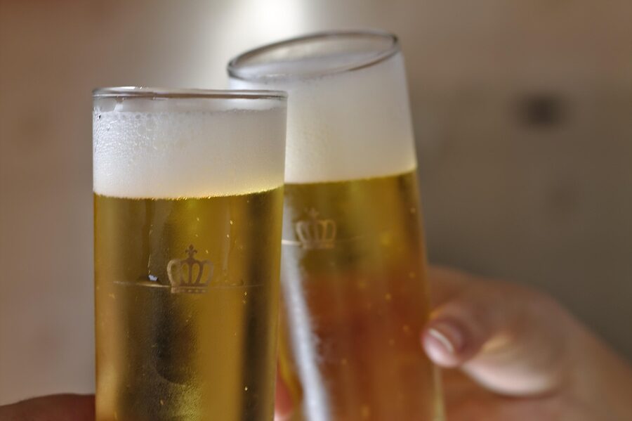 Three friends raising frosted bottles of beer in a toast