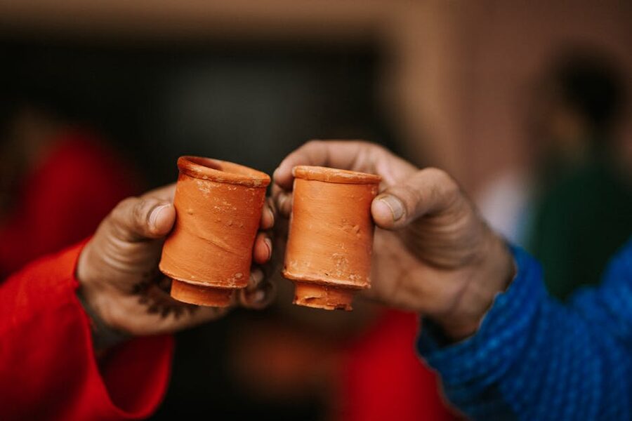 Two hands raising small clay cups in a toast