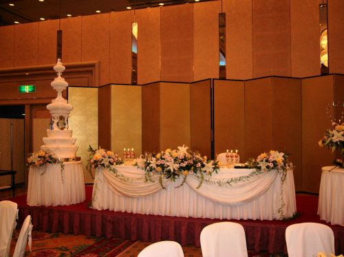 Japanese wedding reception with guests at round tables raising glasses for kanpai