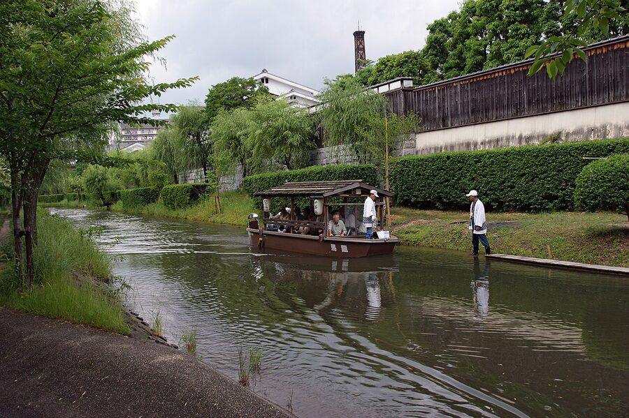Fushimi canal lined with willow trees and traditional sake brewery buildings