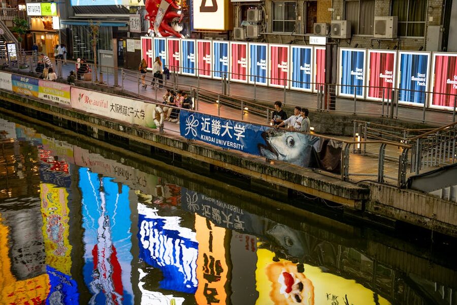 Dotonbori canal at night with billboards reflected in the water and crowds along the walkway