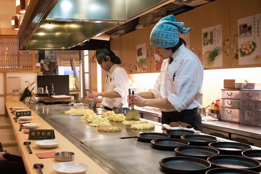 Okonomiyaki chef cooking a Japanese savoury pancake on a hot griddle