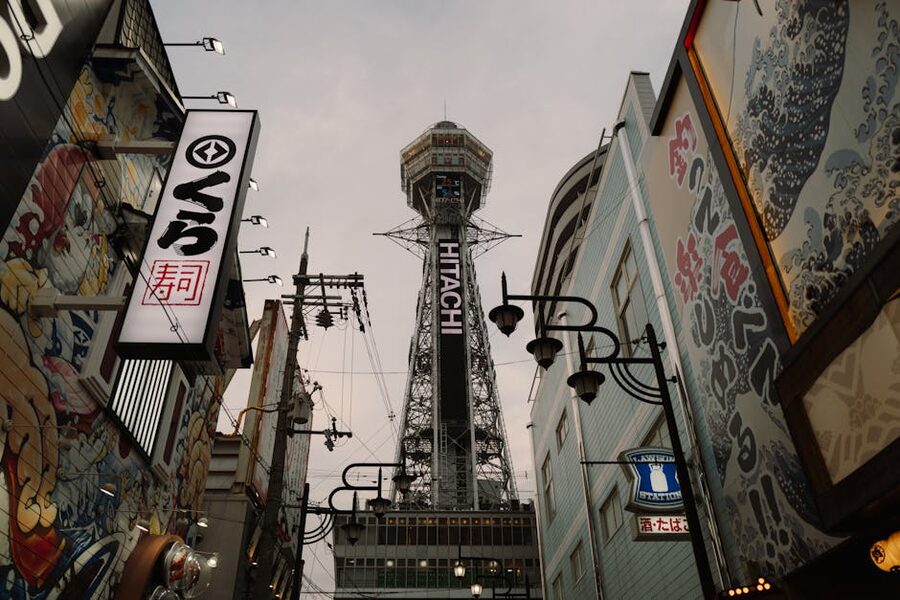 Shinsekai shopfronts in Osaka with the Tsutenkaku tower in the background, vintage signage