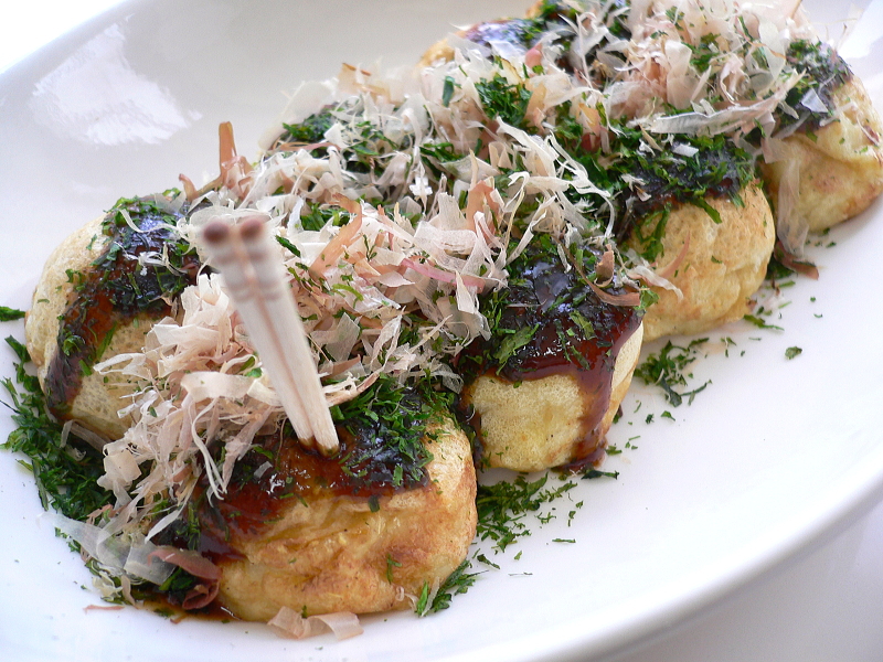 Takoyaki topped with bonito flakes that move from the heat, on a paper tray