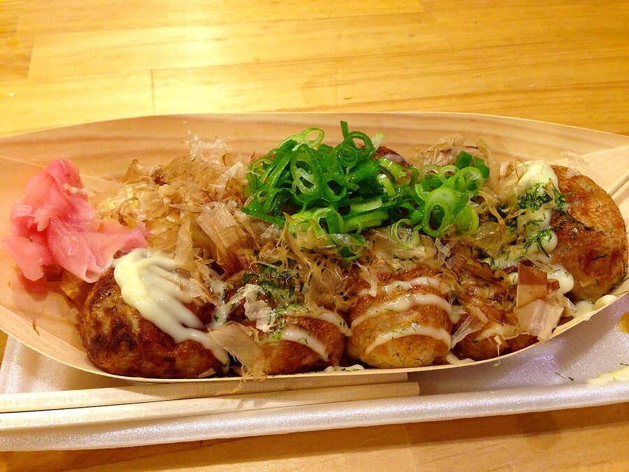 Takoyaki cooking on a hot metal griddle at a street stall in Osaka
