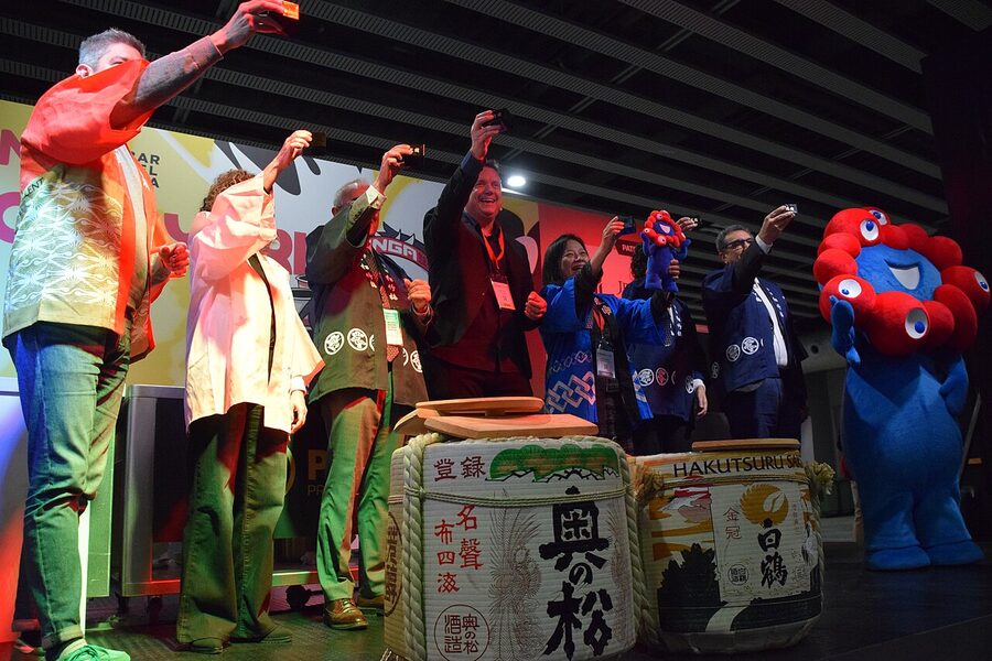 A kagami biraki ceremony with multiple participants striking a sake cask together