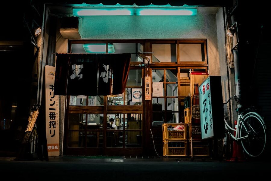 An Osaka izakaya with a neon-lit traditional facade and lanterns, the kind of standing-bar block that runs for half a kilometre