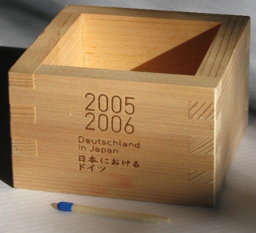Glass of sake placed inside a wooden masu box, overflowing slightly