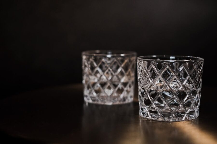 Two crystal glasses on a dark surface in low light