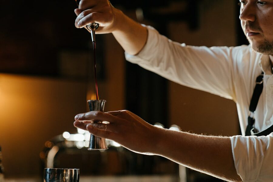 Bartender measuring spirits with a jigger at a bar