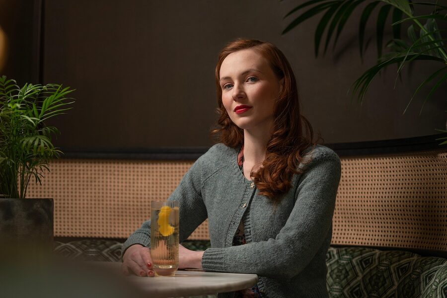 Whisky drinker at counter with two glasses and bottles in background