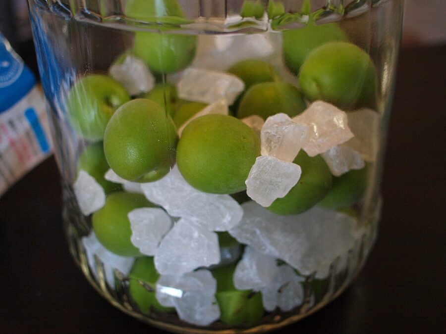 Layered green ume and rock sugar in a glass jar, the classic umeshu setup