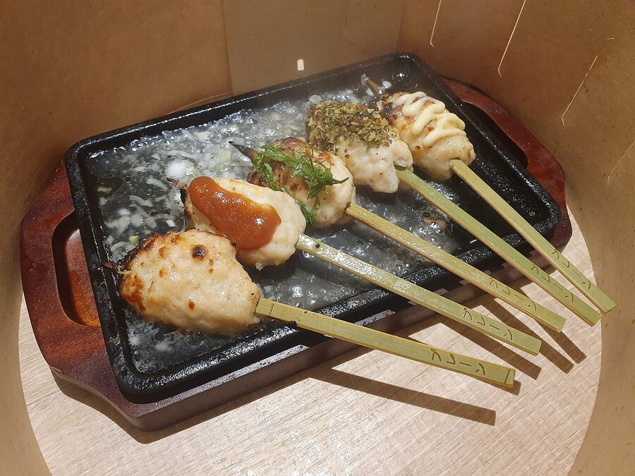 A skewer of tsukune (chicken meatball) glazed and topped with green negi sauce