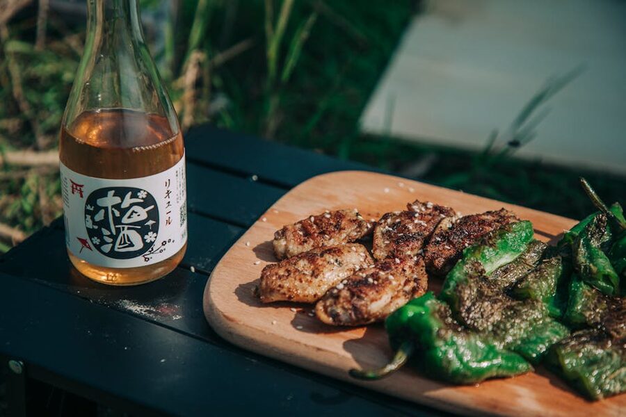 A wooden board of grilled chicken wings with a bottle and glass nearby, ready for pairing