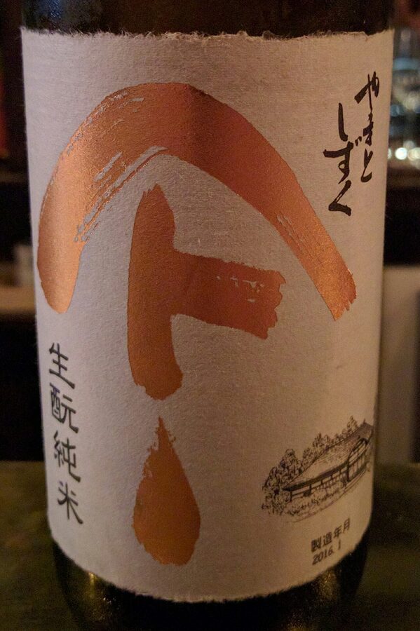 A bottle of Yamato Shizuku kimoto junmai sake on a wooden surface